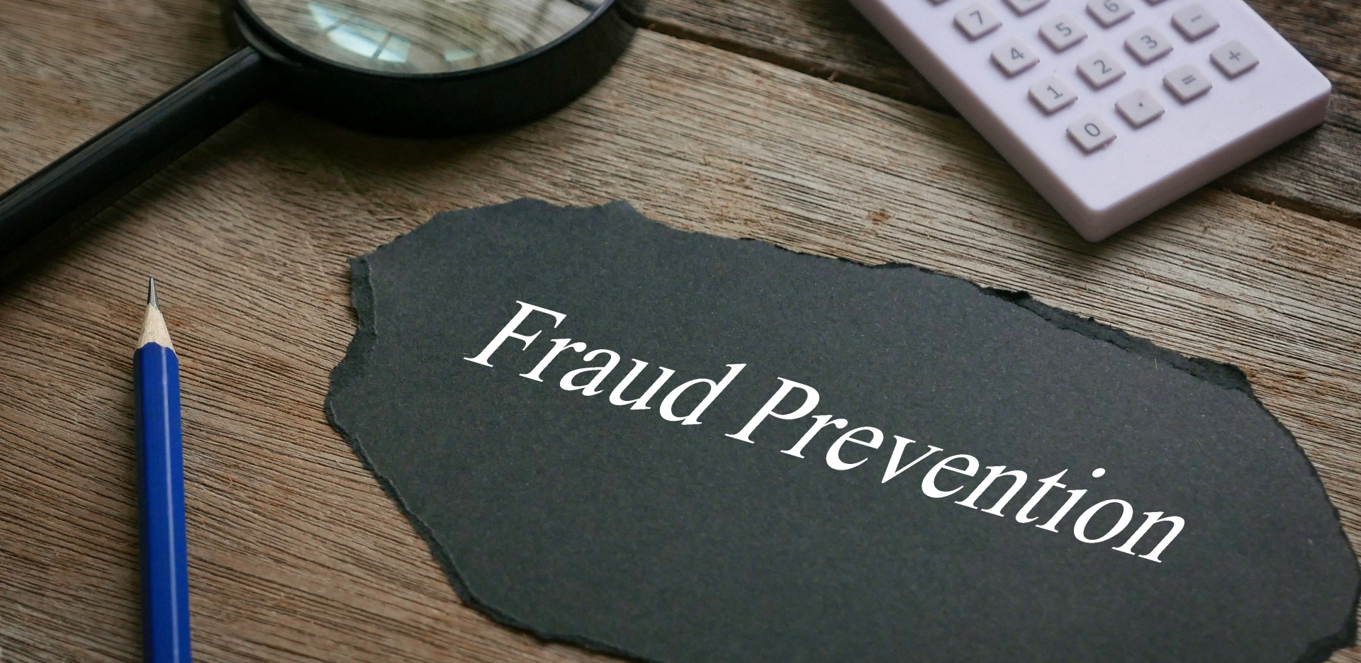 The words "Fraud Prevention" on a desk with a magnifying glass.