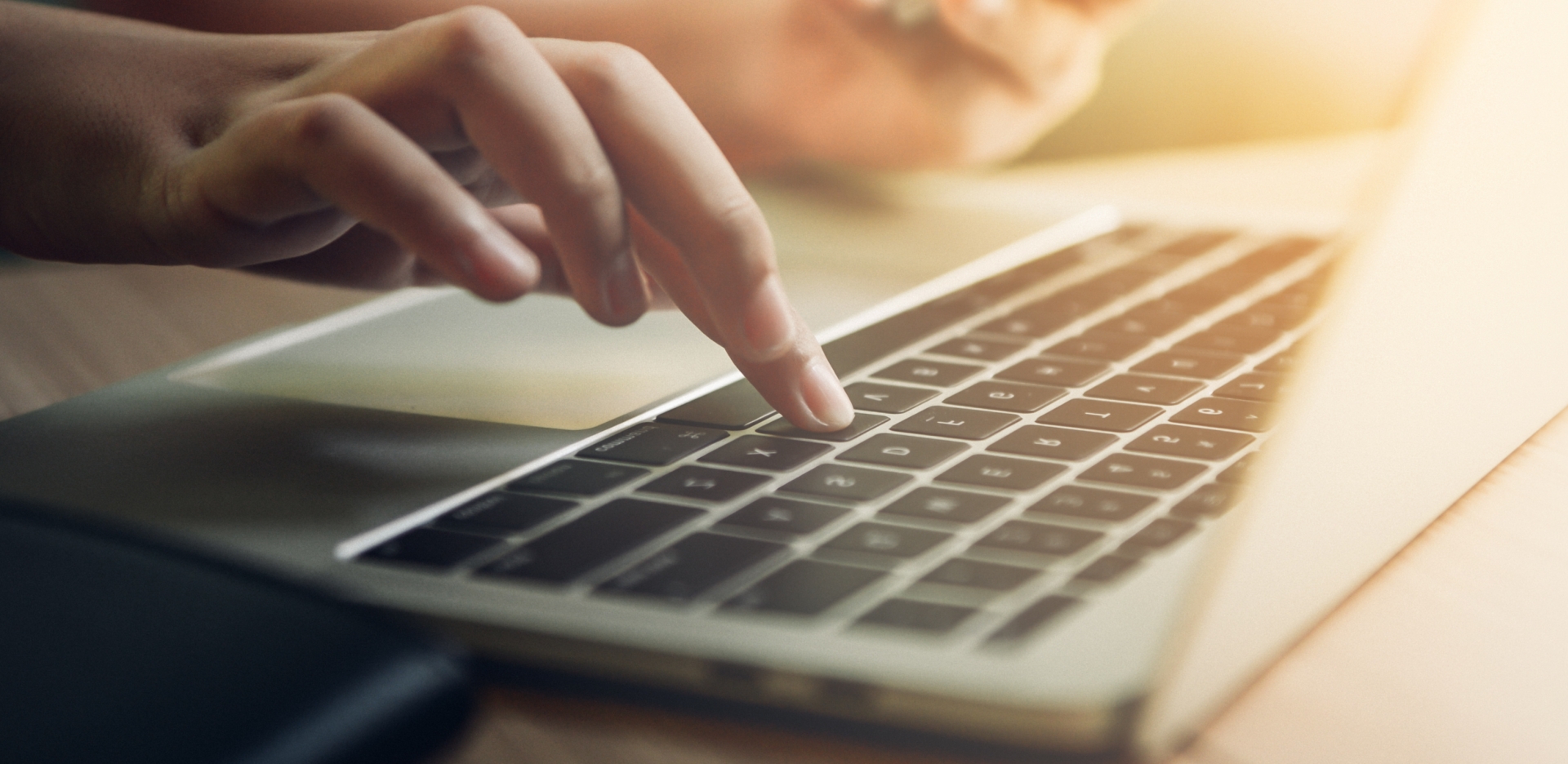 Hands hovering over laptop keyboard, typing in information.