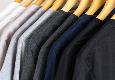 Ten tshirts hanging in a closet. Colors go from white, to light gray, to dark gray, to dark blue, to black.